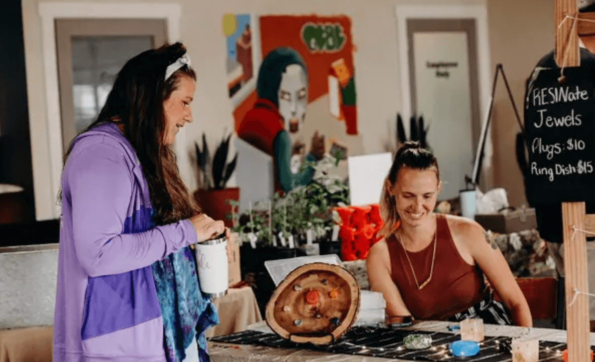 a vendor showing her art to a shopper